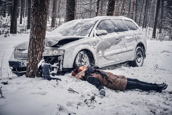 La fille blessée est allongée sur la neige près d'une voiture cassée . — Photo