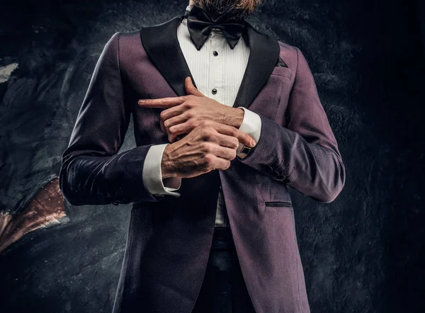 Imagem recortada de um homem barbudo elegante vestido com um terno elegante violeta em pé contra uma parede texturizada escura — Fotografia de Stock