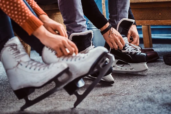 Casal jovem que se prepara para uma patinação. Close-up foto de suas mãos amarrando cadarços de patins de hóquei no gelo no vestiário — Fotografia de Stock