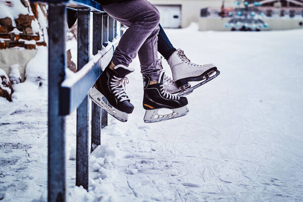 Couple wearing ice skates sitting on a guardrail