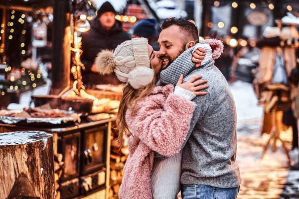 Casal atraente no amor, gostando de passar o tempo juntos enquanto abraçando na feira de inverno em um tempo de Natal — Fotografia de Stock