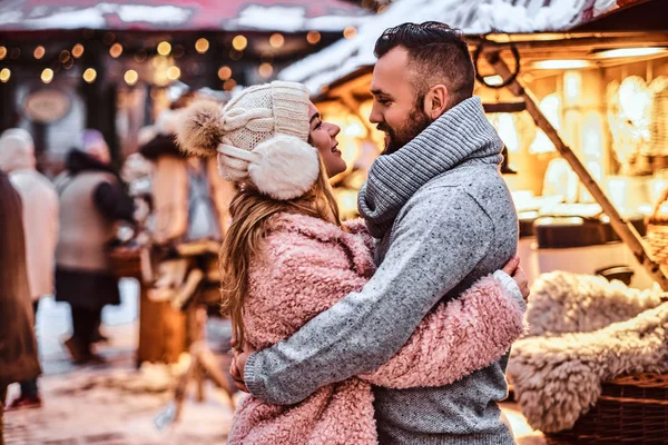 Um homem bonito e encantadora menina abraçando e gostando de passar o tempo juntos, enquanto de pé na feira de inverno em um tempo de Natal — Fotografia de Stock