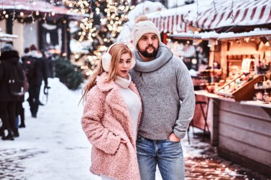 Çekici çift birlikte ayakta sıcak giysiler giyen bir kış bir Noel zamanda adil bir dükkanı sayacı yakınındaki.