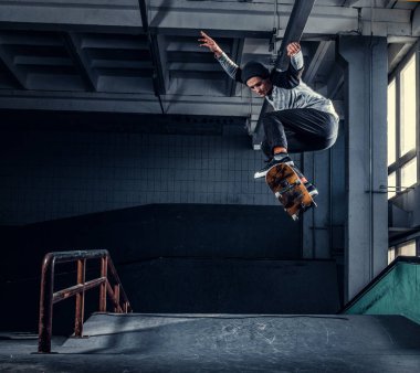 Genç kaykaycı mini rampa skate park kapalı bir numara performans. 