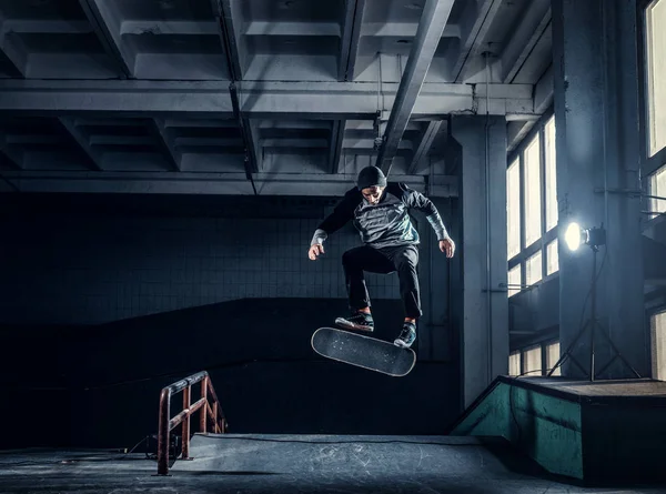 Joven skateboarder realizando un truco en mini rampa en skate park indoor . — Foto de Stock