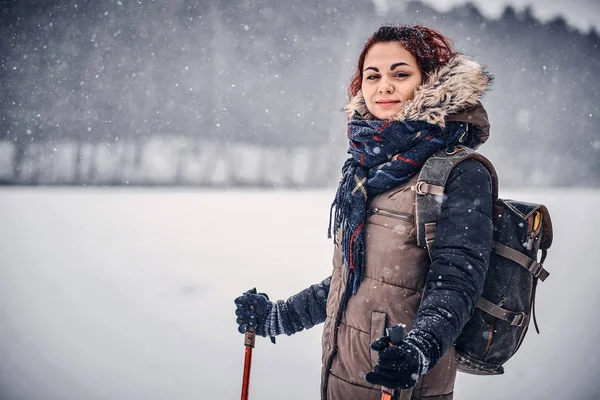 Retrato de uma menina com uma mochila caminhando pela floresta de inverno — Fotografia de Stock