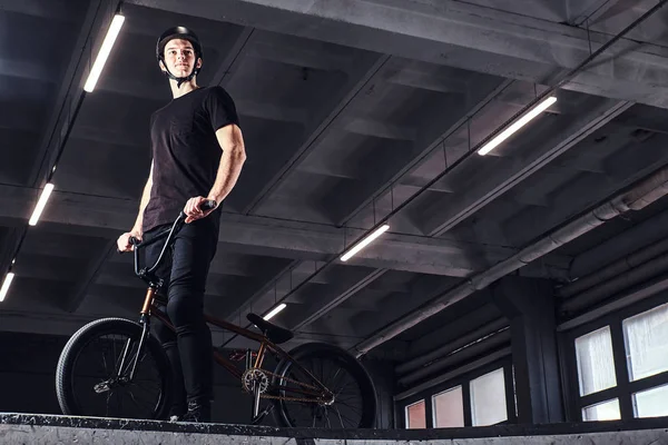 Молодий чоловік з BMX готується стрибати в скейтпарку в приміщенні — стокове фото