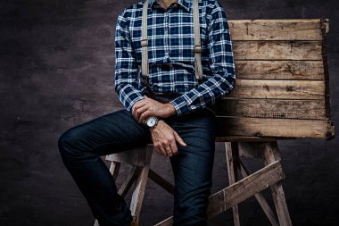 Kırpılmış görüntü. Eski kafalı adam ahşap bir iskele üzerinde oturan askısı ile damalı gömlek giymiş