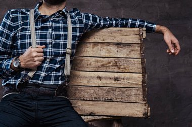 Kırpılmış görüntü. Eski kafalı adam ahşap bir iskele üzerinde oturan askısı ile damalı gömlek giymiş