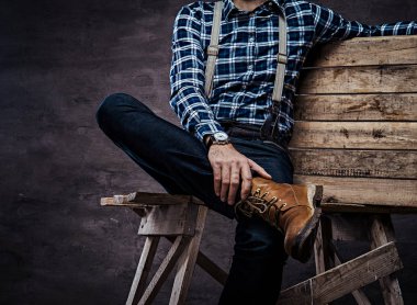 Kırpılmış görüntü. Eski kafalı adam ahşap bir iskele üzerinde oturan askısı ile damalı gömlek giymiş