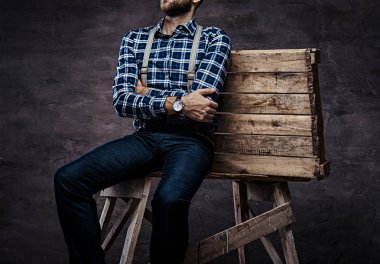 Kırpılmış görüntü. Ahşap bir iskele üzerinde oturan eski kafalı adam bir kareli gömlek askısı kolları ile geçti