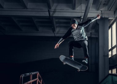 Genç kaykaycı mini rampa skate park kapalı bir numara performans. 