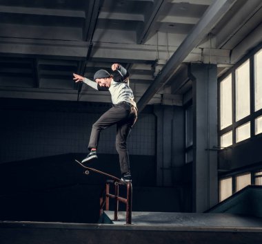 Genç kaykaycı mini rampa skate park kapalı bir numara performans. 