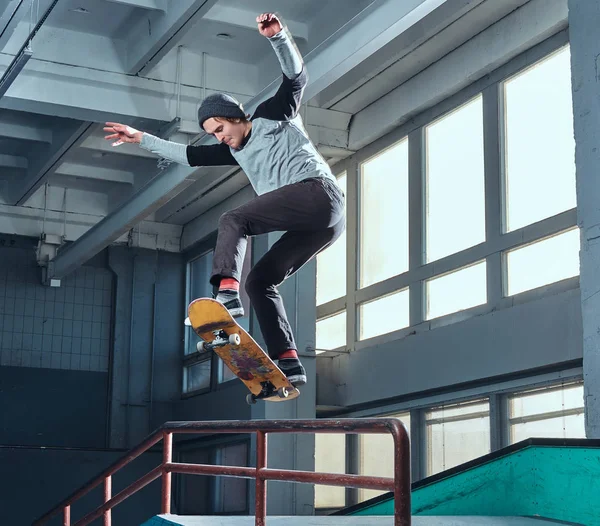 Молодий скейтбордист виконує трюк на міні гонці в скейт-парку в приміщенні . — стокове фото