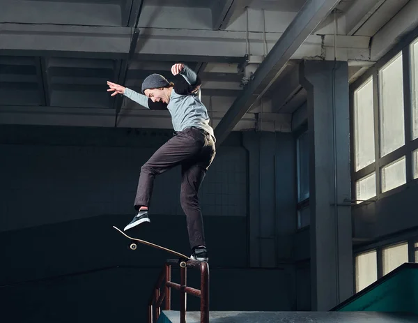 Jonge skateboarder uitvoeren van een truc op mini hellingshoek op indoor Skatepark. — Stockfoto