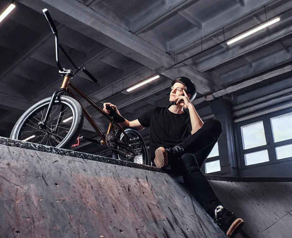Bmx 라이더는 skatepark 실내에 그의 자전거 트릭 연습 후 휴식 — 스톡 사진