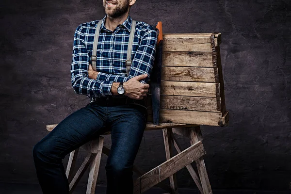 Imagen recortada. Trabajador, carpintero, manitas con camisa a cuadros con tirantes sentados en un andamio de madera — Foto de Stock