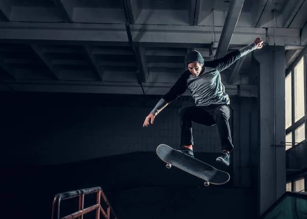 Молодой скейтбордист выполняет трюк на мини-рампе в скейт-парке в помещении . — стоковое фото