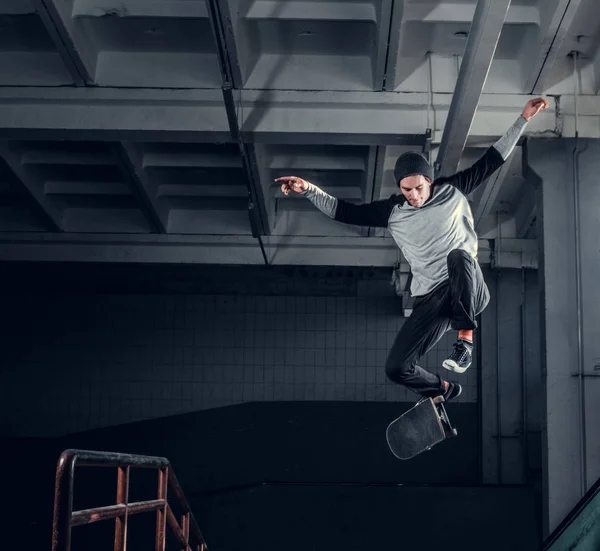 Jonge skateboarder uitvoeren van een truc op mini hellingshoek op indoor Skatepark. — Stockfoto