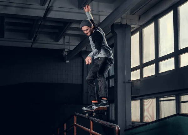 Jonge skateboarder uitvoeren van een truc op mini hellingshoek op indoor Skatepark. — Stockfoto