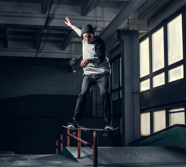 Jonge skateboarder uitvoeren van een truc op mini hellingshoek op indoor Skatepark. — Stockfoto