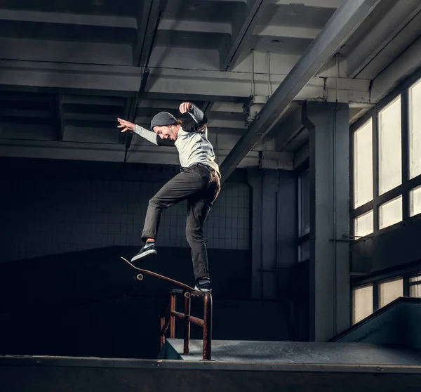 Jonge skateboarder uitvoeren van een truc op mini hellingshoek op indoor Skatepark. — Stockfoto