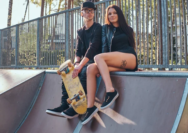 Pareja enamorada sentados juntos en una rampa en el parque de skate en el verano —  Fotos de Stock