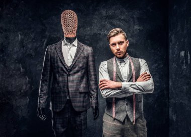 Karanlık terzi Studio özel özel yapılmış mens kıyafetli bir manken yanında poz kendine güvenen genç moda tasarımcısı 