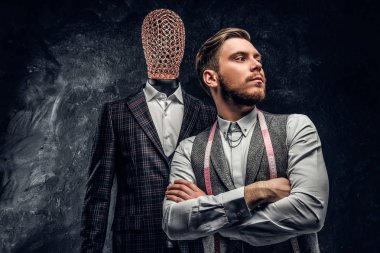 Karanlık terzi Studio özel özel yapılmış mens kıyafetli bir manken yanında poz kendine güvenen genç moda tasarımcısı 