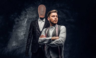 Karanlık terzi Studio özel özel yapılmış mens kıyafetli bir manken yanında poz kendine güvenen genç moda tasarımcısı 