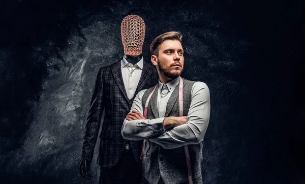 Karanlık terzi Studio özel özel yapılmış mens kıyafetli bir manken yanında poz kendine güvenen genç moda tasarımcısı 