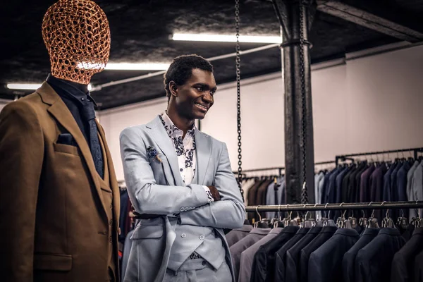 Afroamerikansk man klädd i blå elegant kostym poserar med korsade armar i en klassiska herrkläder butik. — Stockfoto