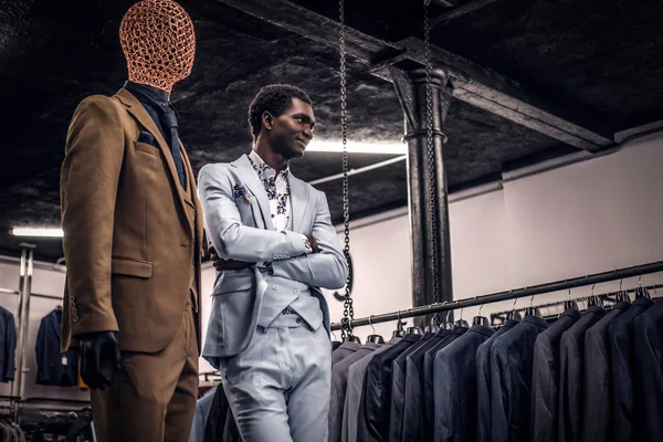 Uomo afro-americano vestito di blu elegante vestito in posa con le braccia incrociate in un classico negozio di abbigliamento maschile . — Foto Stock