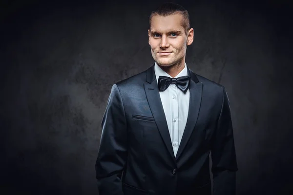 Portrait of a handsome stylish wearing elegant classical suit with a bow tie. — Stock Photo, Image
