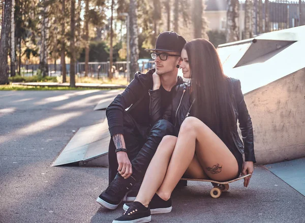 Pareja enamorada junta se sienta en un monopatín en un parque de skate en el verano —  Fotos de Stock