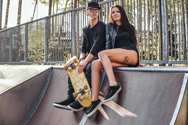 Pareja enamorada sentados juntos en una rampa en el parque de skate en el verano —  Fotos de Stock