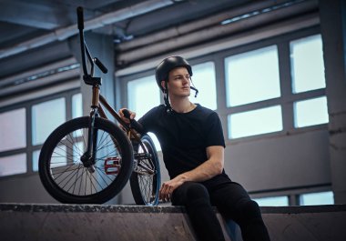 BMX sürücüsü hileler bir skatepark kapalı onun bisiklet ile pratik sonra rahatlatıcı