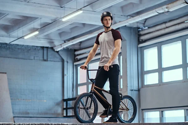 Молодий чоловік з BMX готується стрибати в скейтпарку в приміщенні — стокове фото