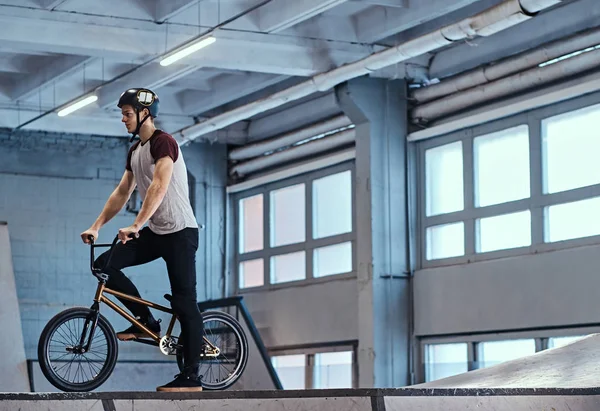 Jeune homme avec BMX se préparer à sauter dans un skatepark à l'intérieur — Photo