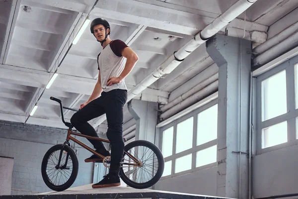 Joven con BMX preparándose para saltar en un parque de skate en el interior — Foto de Stock