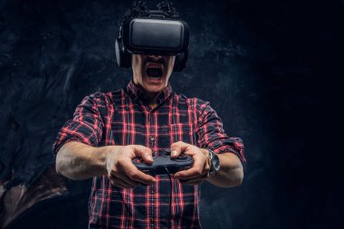 Duygusal adam VR kulaklık kullanarak ve joystick ile bilgisayar oyunu bir stüdyoda karanlık duvar arka plan karşı oynamak.