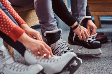Genç bir çift bir paten için hazırlanıyor. Yakın çekim fotoğraf ellerinin buz hokeyi ayakkabı bağcığı bağlama soyunma odasında skates