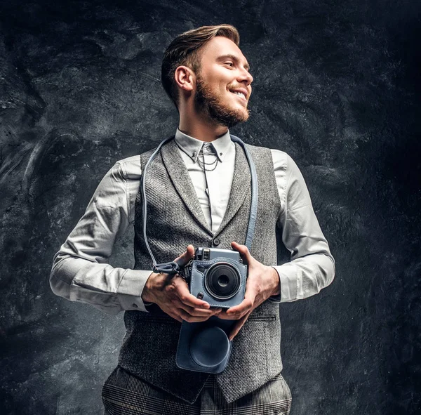 Elegantemente vestido jovem posando com uma câmera em um estúdio — Fotografia de Stock