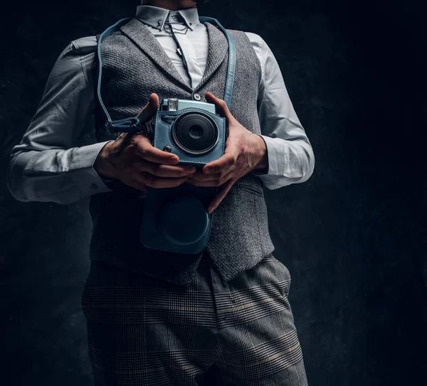 Elegantemente vestido jovem posando com uma câmera em um estúdio — Fotografia de Stock