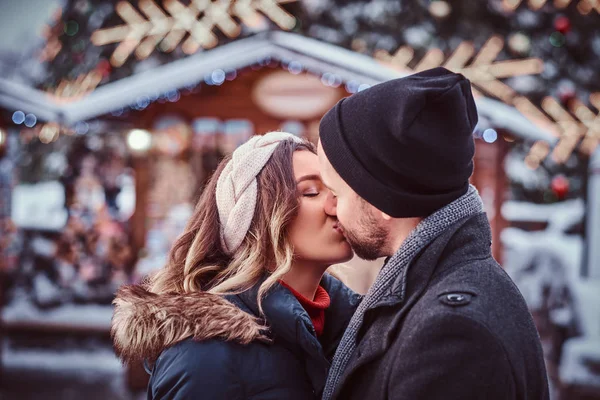 Pareja joven y feliz vistiendo ropa abrigada de pie cerca de un árbol de Navidad de la ciudad, disfrutando pasar tiempo juntos — Foto de Stock