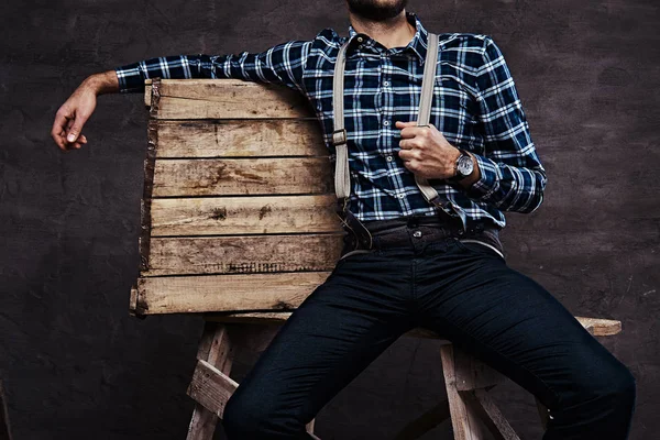 Abgeschnittenes Bild. altmodischer Mann mit kariertem Hemd und Hosenträgern, der auf einem Holzgerüst sitzt — Stockfoto