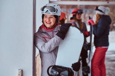 Bir snowboard kış kayak tatil ile poz gülümseyen kadın giyiyor kış spor