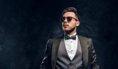 Güneş gözlüklü bir karanlık dokulu duvara şık bir takım elbise giymiş şık bir adam