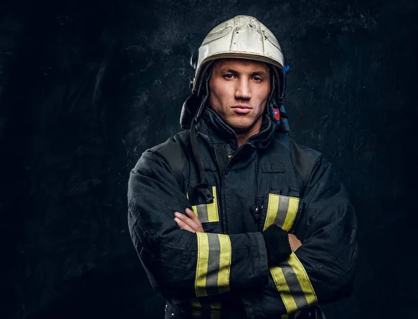 Brutaler Feuerwehrmann in Uniform posiert mit verschränkten Armen und selbstbewusstem Blick für die Kamera. — Stockfoto