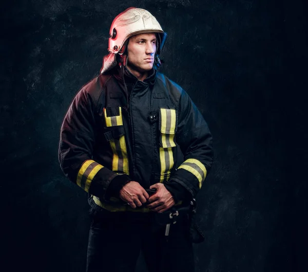 Portrait of firefighter dressed in uniform and safety helmet looking sideways with a confident look — Stock Photo, Image